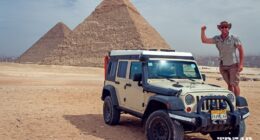 Dan Grec stands on his Jeep with pyramids in background.