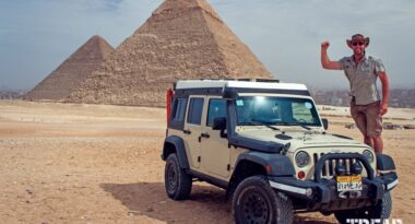 Dan Grec stands on his Jeep with pyramids in background.