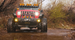 Red Jeep drives through creek on Steal Bender Trail in Moab, Utah.