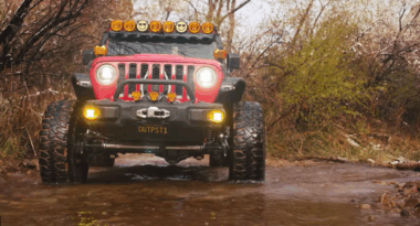 Red Jeep drives through creek on Steal Bender Trail in Moab, Utah.