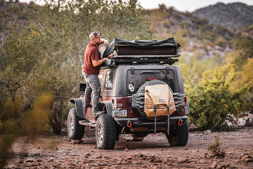 Chris steps up on his tire to pop up his Simttybuilt roof top tent
